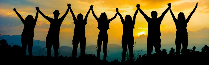 silhouettes of seven people linking their hands in the air